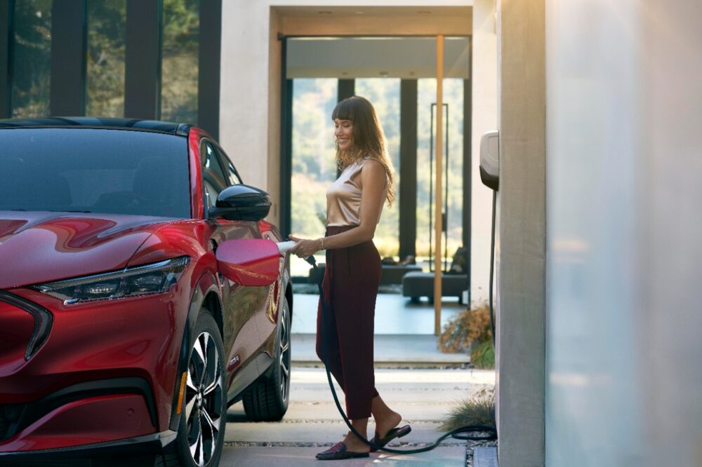 Side shot of woman charging her EV Mustang